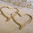 Two heart shapes drawn in sand on a beach, with gentle waves washing over the left heart while the right heart remains intact.