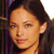 Pixelated close-up of a person with dark hair, light skin, and a neutral expression, cropped to show head and shoulders against a dark background.