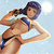 Pixelated image of a person in a bikini top with dark straps, holding a white object near their face against a light blue background.