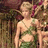 Pixelated image of a person with light hair wearing a green and white patterned top, standing against a blurred background.