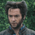 Pixelated image of a person with dark hair and a beard, wearing a blue-collared shirt against a green foliage background.