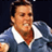 Static pixelated image of a person in a blue and white sports jersey with visible facial features, cropped to show upper body against dark background.