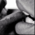 Static grayscale icon showing a close-up of lips and teeth with partial facial features, rendered in low-resolution pixel art style.