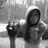 A grayscale animated icon shows a hooded figure with long hair holding an object, positioned next to a dark cylindrical prop against a blurred background.