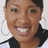 Pixelated close-up of a smiling person with short dark hair wearing a black top against light background.