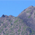Pixelated landscape with blue sky and rocky terrain featuring green patches and dark spots.