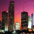 Pixelated cityscape at dusk with tall buildings against a purple-orange sky, next to green text reading "Original Icons .com" on dark background.