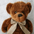 Brown teddy bear with cream bow tie on light gray background, blue pixelated text on bright pink
