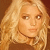 Pixelated close-up of a person with long blonde hair against a brown background, static image.
