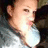 Pixelated close-up of a person's face with light skin tone, brown hair visible on the left side, wearing dark clothing and a white shirt underneath.