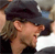 A pixelated close-up of a person with light brown hair wearing a dark cap, viewed from the side with a blurred background.
