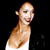Pixelated static image of a person with light skin tone, short hair, and a white top against a dark background.