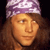 Pixelated close-up of a person with long brown hair wearing a purple and white patterned headband against a dark background.