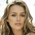 A static pixelated image of a person with light brown wavy hair, neutral expression, and visible ear, cropped to show head and shoulders against a white background.