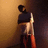 Pixelated figure in dark clothing holding a light-colored object against a gradient background transitioning from brown to dark tones.