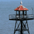 A pixelated static image of a tower with a red roof and black metal framework against a blue background.