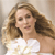 A pixelated image of a person with long brown hair wearing a white sleeveless top against a light brown background.