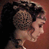 Pixelated static image of a person's profile with dark hair and light skin against a reddish-brown background.