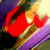 A pixelated red and gold object with curved shapes against a multicolored background of purple, green, yellow, and black.