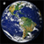Pixelated globe showing Earth with blue oceans, green landmasses, and white clouds against a black background, with a small white square in the top-left corner.