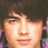Pixelated close-up of a person's face with dark hair, light skin, and a neutral expression against a dark background.