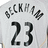 Pixelated image of a light gray sports jersey with black text and numbers, featuring a stylized 'L' and 'K' logo on the left shoulder and a checkered flag on the right shoulder.