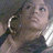 Pixelated static image of a person with light skin tone, dark hair tied back, wearing a white headband and dark clothing against a muted background.