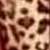 Pixelated static image with brown and beige tones showing indistinct shapes resembling abstract forms or partial symbols.