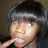 A person with short dark hair and bangs holds a finger near their mouth across four showing slight head movement