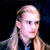 Static pixelated image of a person with light hair and dark clothing against a black background, rendered in low resolution with visible dithering and color blending.