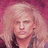 Pixelated close-up of a person with light-colored curly hair against a pinkish-red background, wearing dark clothing.
