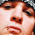 A pixelated close-up of a person's face showing eyes, nose, and mouth with reddish-brown hair visible at the top edge.
