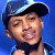 Pixelated image of a person wearing a dark cap with light trim, smiling against a blue background.