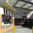 Static pixelated image of a building facade with a large awning, dark windows, and a red sign element, set against a light background.