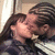 Two people in a close embrace, one with long dark hair and the other with braided hair, sharing an intimate moment against a striped background.