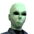 Green-skinned alien with large black eyes and a bald head appears in three sequential views showing slight facial angle shifts.