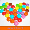 Heart-shaped arrangement of colorful round candies with 'sweet heart' text on colored bars below.