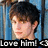 Pixelated image of a person with dark hair and light skin, wearing a dark top against a blue background with white vertical lines, with text at the bottom reading "Love him!".