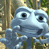 Pixelated blue creature with large black eyes and a wide mouth, set against a blurred forest background with brown and green tones.