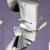 Pixelated figure in white attire with black accents against a purple background, holding a long object.