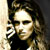 Pixelated static image of a person with long wavy hair wearing dark clothing against a light background, rendered in low-resolution 256x256 pixels.