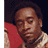 Static 48x48 pixel buddy icon showing a close-up of a person's face with dark curly hair, wearing a red garment and light-colored patterned shirt against a dark background.