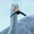 Pixelated static image of a light blue bird-like figure with outstretched wings against a pale sky background.