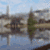 Pixelated landscape with water reflecting buildings and trees, overlaid with text questioning reflection direction.