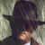 A pixelated static image shows a person wearing a dark fedora hat and dark clothing against a muted greenish background.