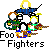 Pixelated animation of a figure with yellow hair and blue clothing playing drums, surrounded by musical instruments on gray background.