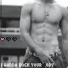 A black-and-white image of a shirtless muscular man with a necklace, standing in front of a blurred background with text and heart symbols.
