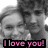 A grayscale pixelated image of two people in close proximity with a pink text banner reading "I love you!" at the bottom.