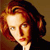 Pixelated portrait of a person with reddish-brown hair styled in a side part, wearing a dark garment against a warm-toned background.