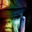 Pixelated static image showing a figure with dark hair, light-colored clothing, and a blurred background of warm and cool tones.